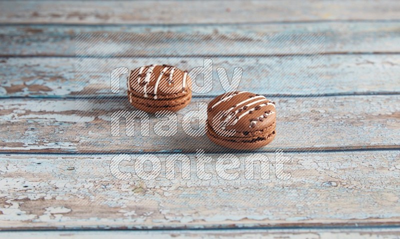 45º Shot of two Brown white  Chocolate Caramel macarons on light blue wooden background