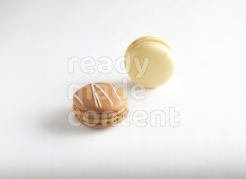 45º Shot of of two assorted Brown Irish Cream, and Yellow Vanilla macarons on white background