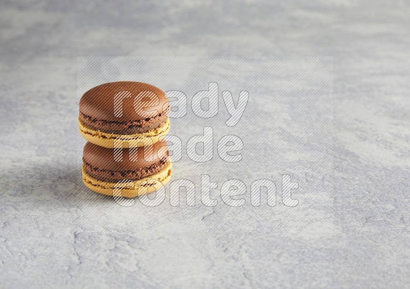 45º Shot of two Yellow and Brown Chai Latte macarons r on white  marble background