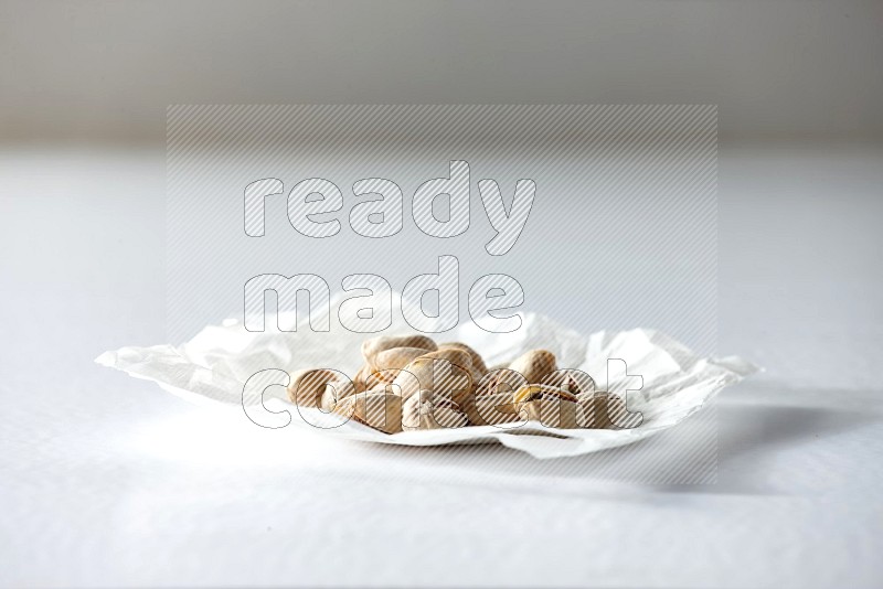 Pistachios on a crumpled piece of paper on a white background in different angles