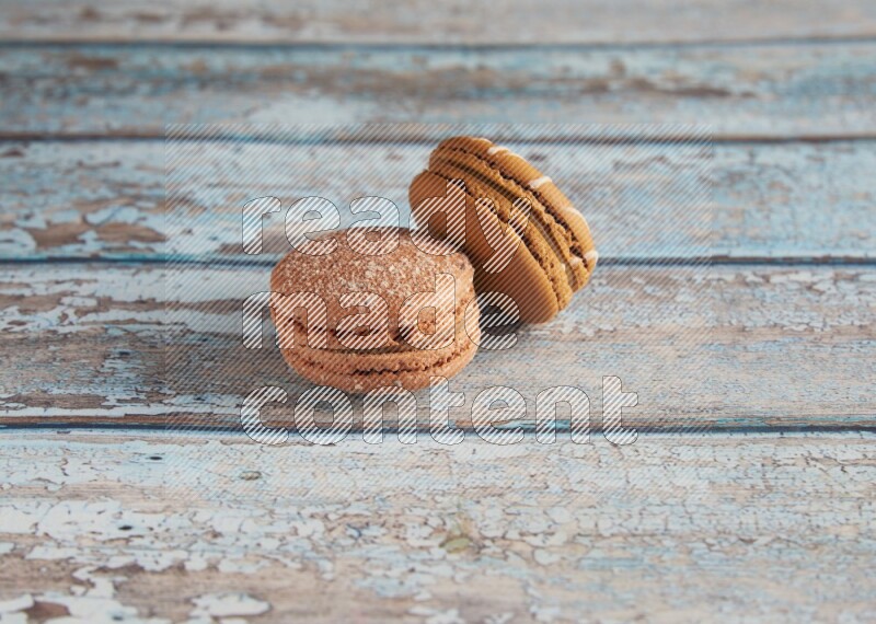 45º Shot of of two assorted Brown Irish Cream, and Brown Hazelnuts macarons  on light blue background