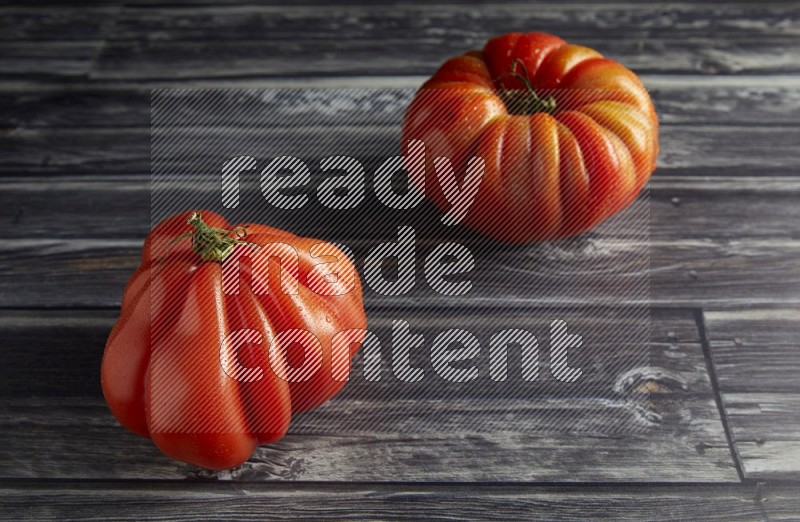 45 degree two heirloom tomato on a textured grey wooden background