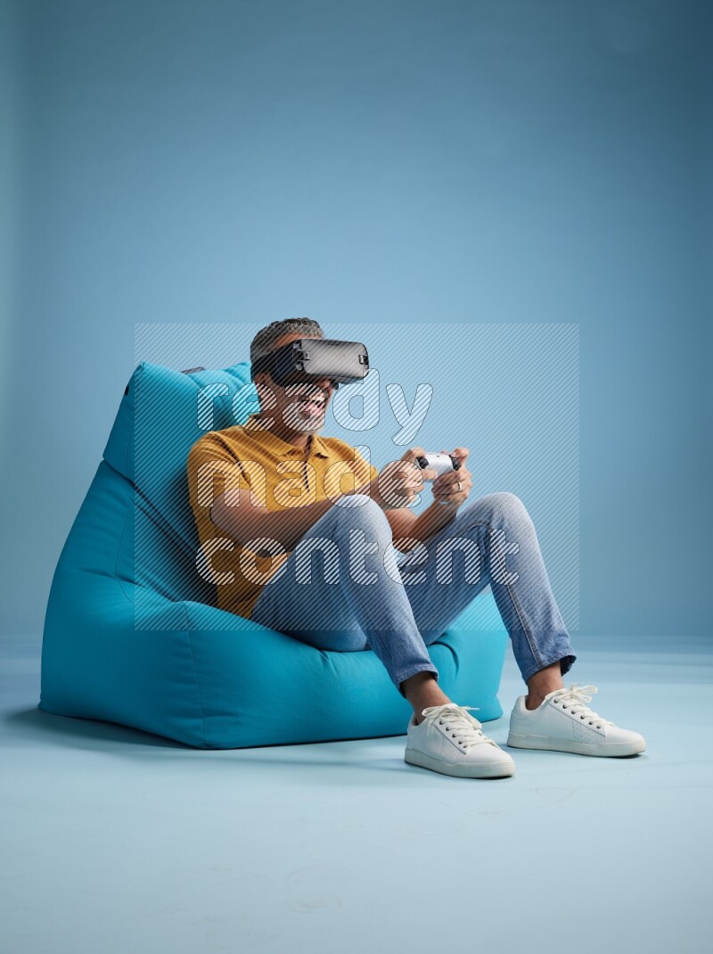 A man sitting on a blue beanbag and gaming with VR