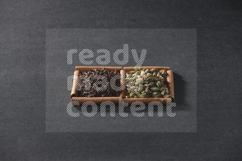 2 squares of cinnamon sticks full of cardamom and cloves on black flooring