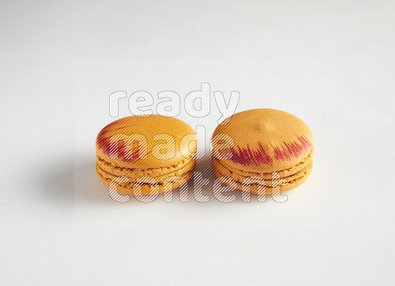 45º Shot of two orange Exotic macarons on white background