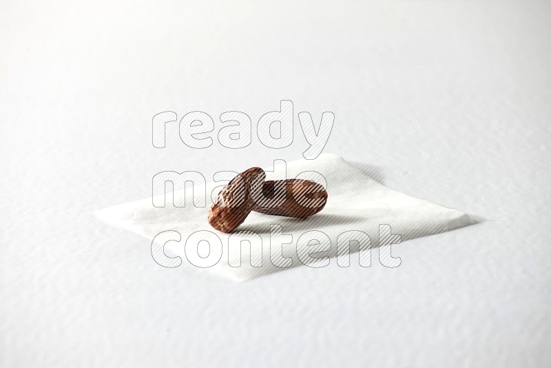 Two dried dates on a piece of paper on a white background in different angles