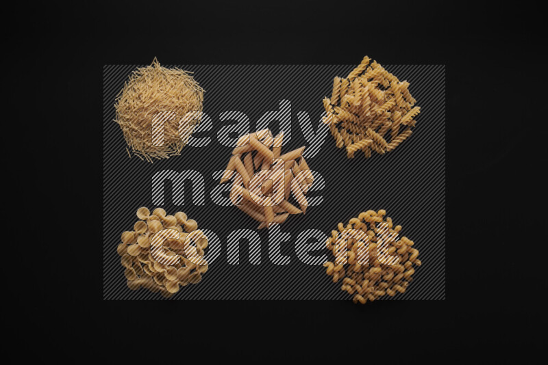 Different pasta types in bunches on black background