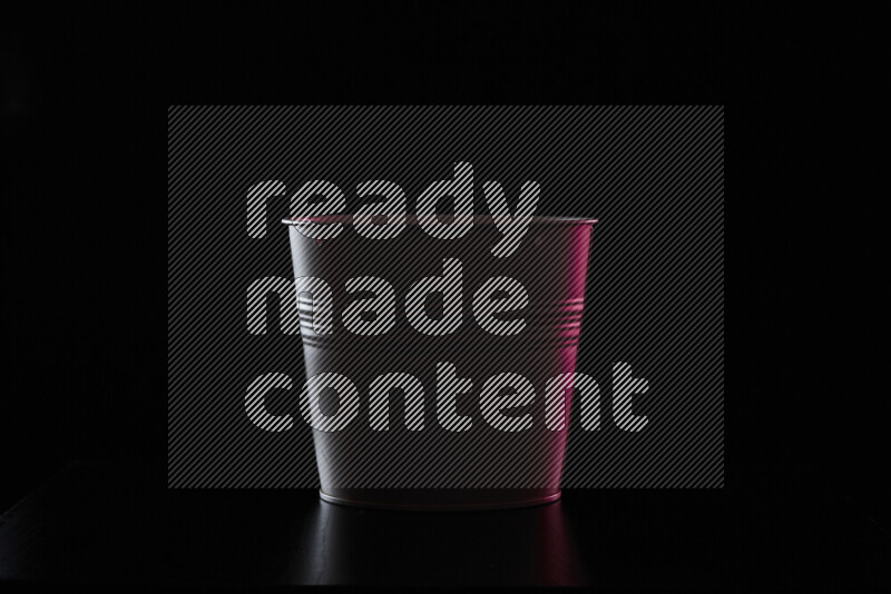 A plant pot with colored rim light against black background