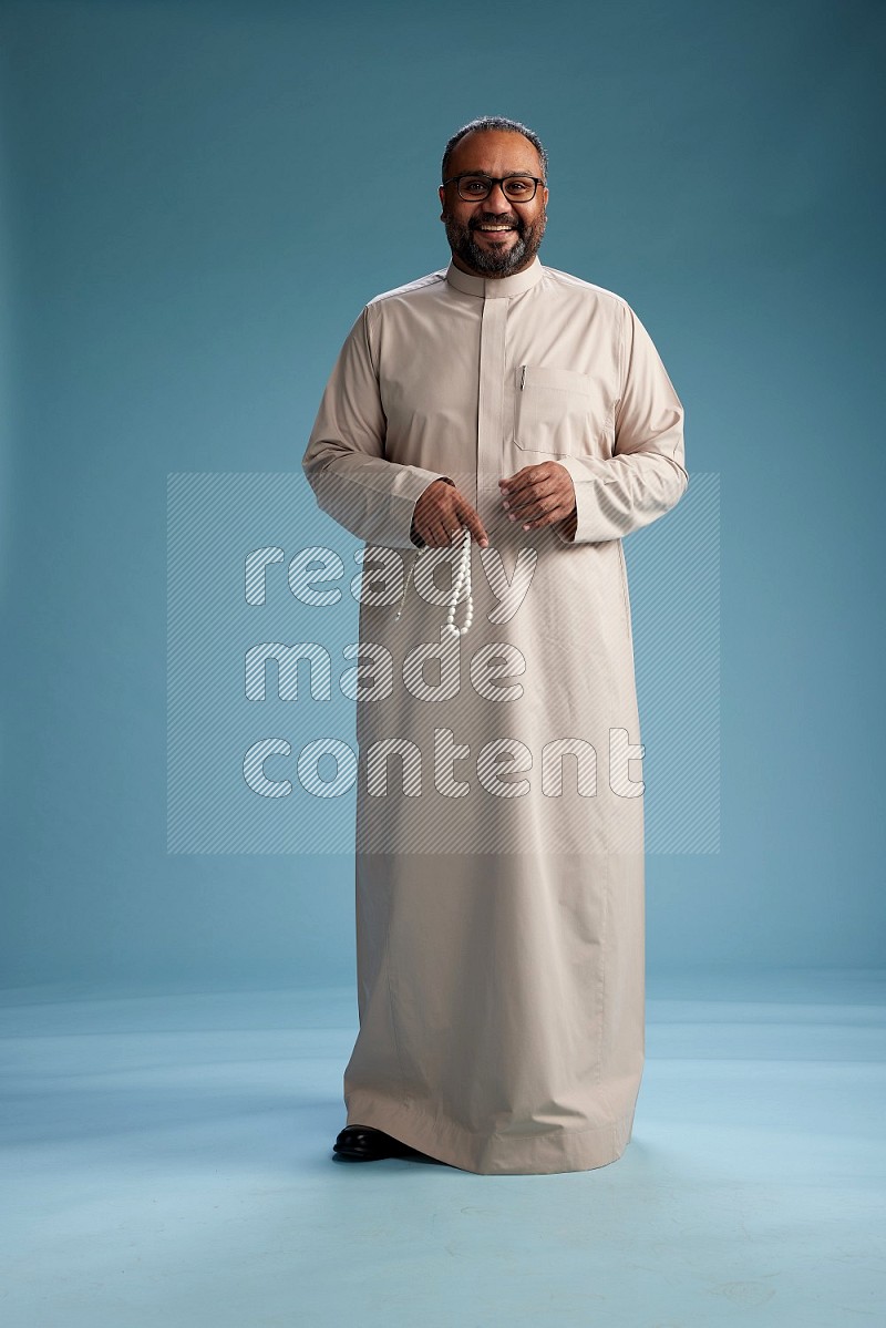 Saudi Man without shimag Standing Interacting with the camera on blue background
