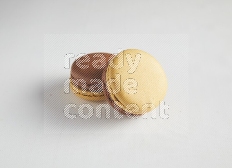 45º Shot of two Yellow and Brown Chai Latte macarons on white background