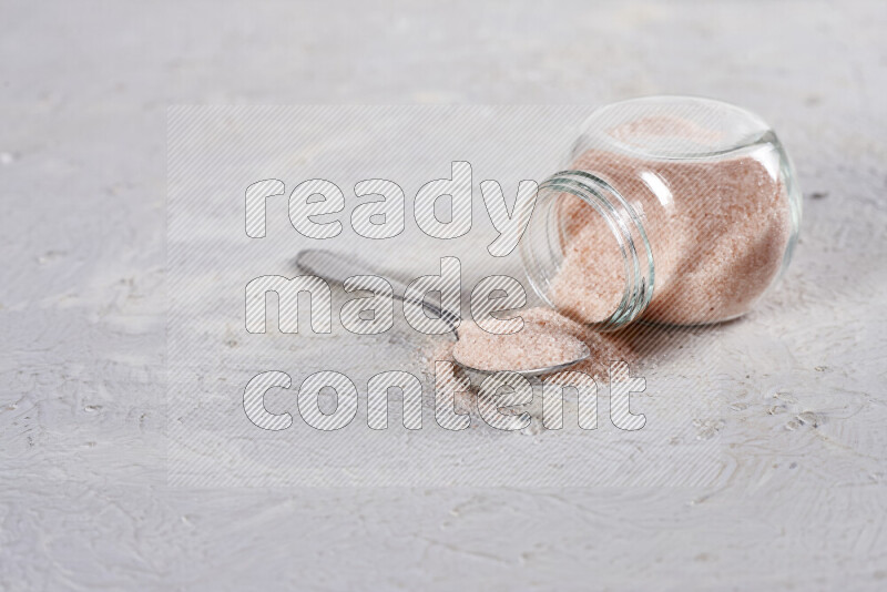 A glass jar full of fine himalayan salt on white background