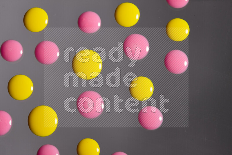 Close-ups of abstract pink and yellow paint droplets on the surface