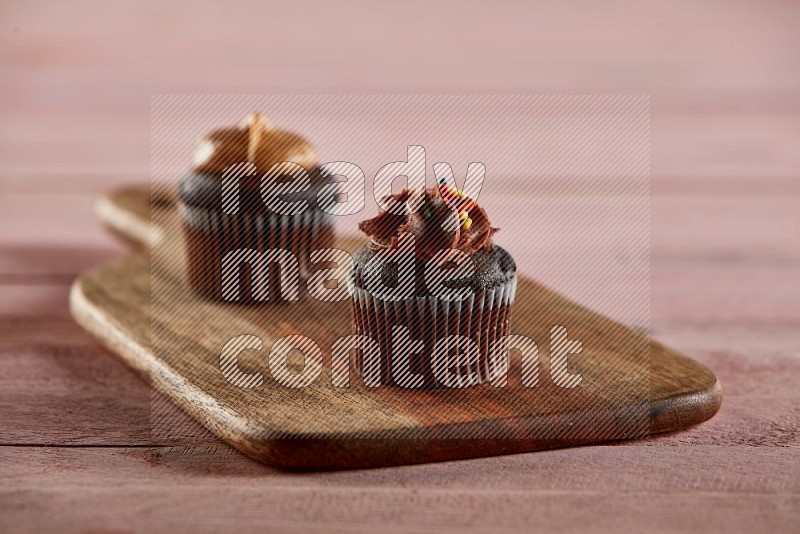 Chocolate mini cupcake topped with chocolate cream on a wooden board