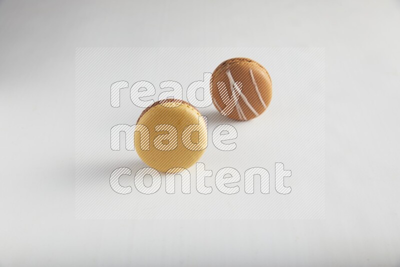 45º Shot of of two assorted Brown Irish Cream, and Yellow, and Brown Chai Latte macarons on white background