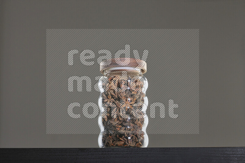 Star anise in a glass jar on black background