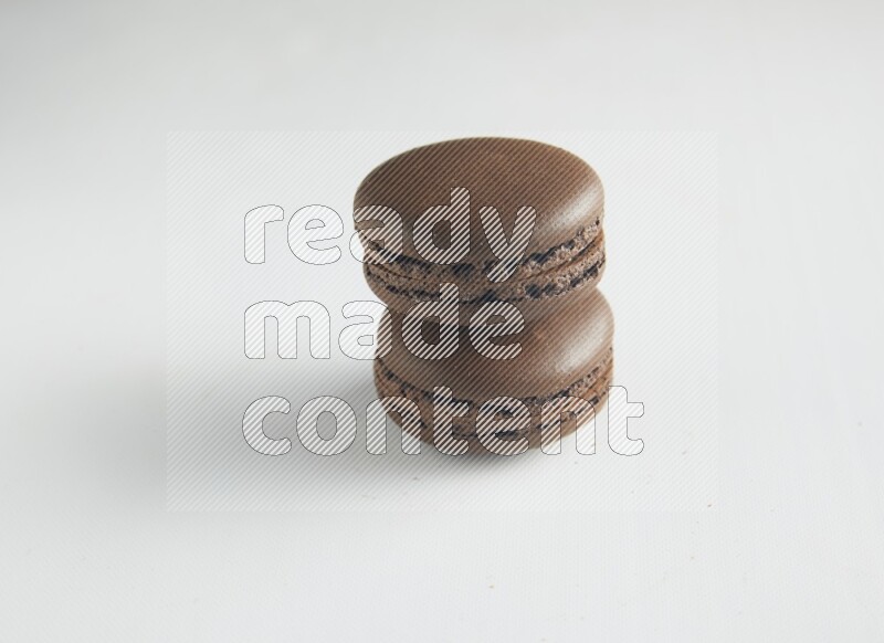 45º Shot of two Brown Dark Chocolate macarons on white background