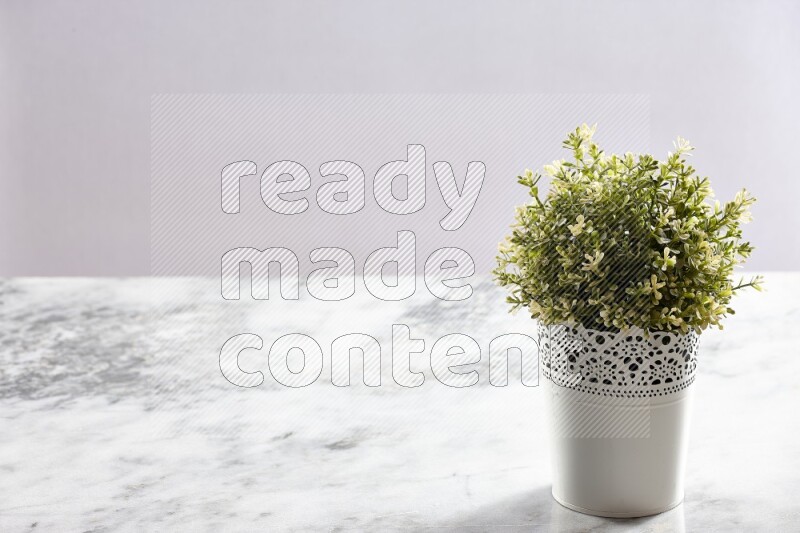 Artificial plant in white decorative pot on grey marble background