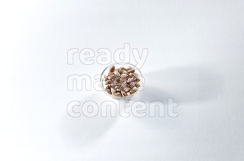 A glass bowl full of peeled pistachios on a white background in different angles