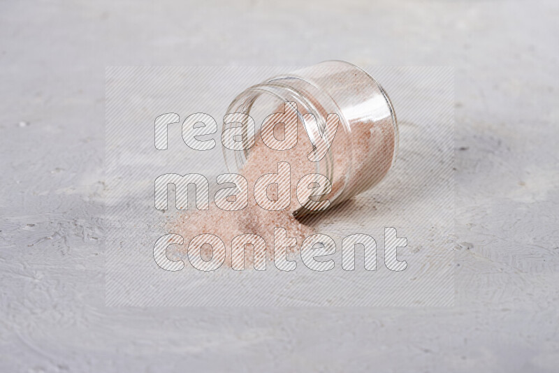 A glass jar full of fine himalayan salt on white background