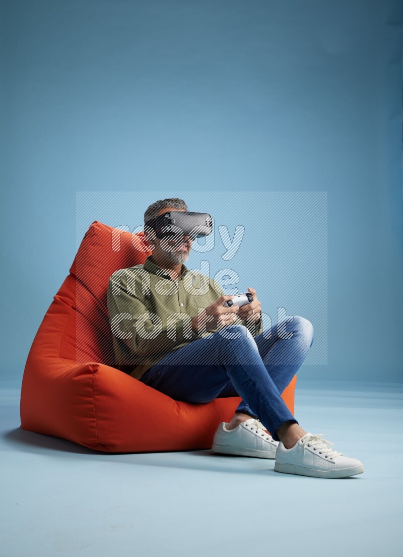 A man sitting on an orange beanbag and gaming with VR