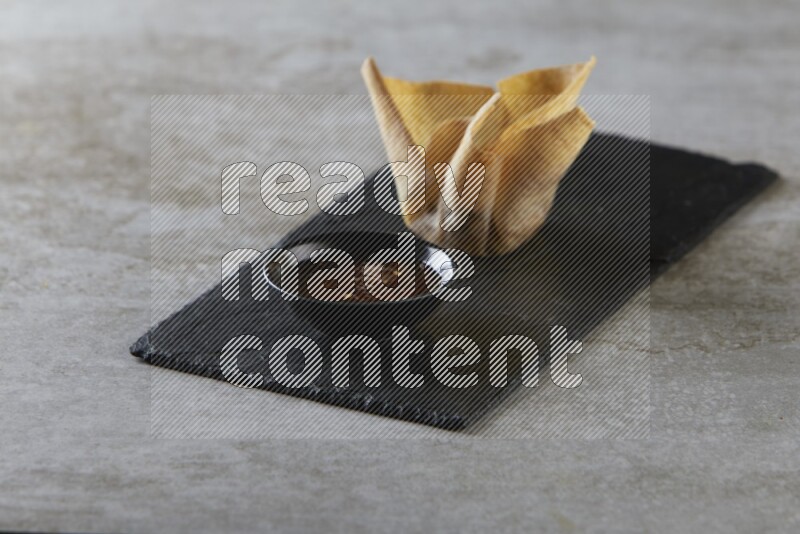 wonton cups with soy sauce ramkin on rectangle slate on grey textured counter top