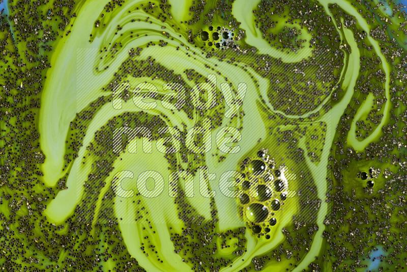 A close-up of sparkling gold glitter scattered on swirling green background