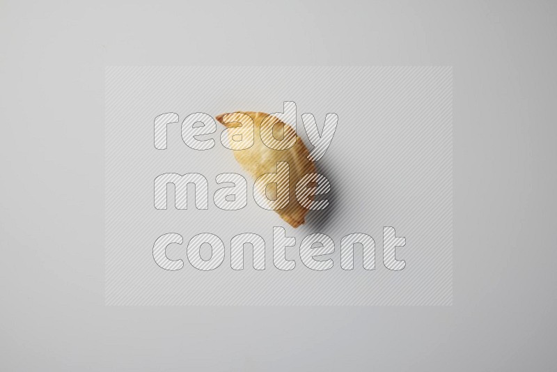 One fried sambosa from a top angle on a white background