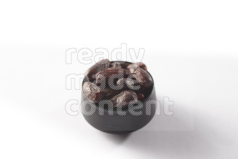 Dates in a black pottery bowl on white background