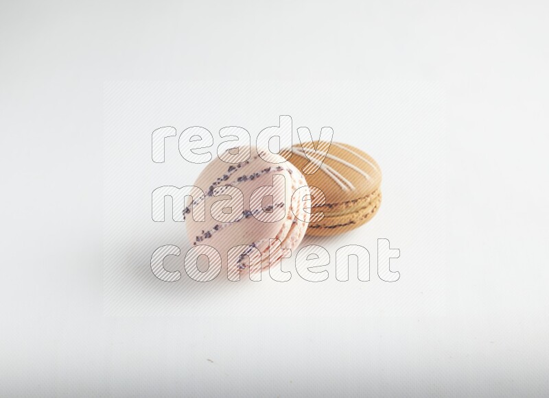 45º Shot of of two assorted Brown Irish Cream, and pink orange blossom macarons on white background