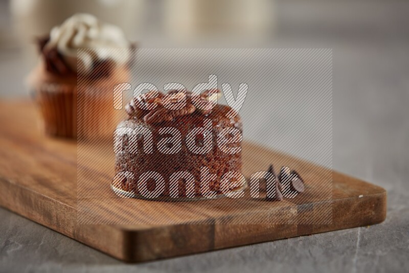 Chocolate cupcake topped with pecan on a wooden board
