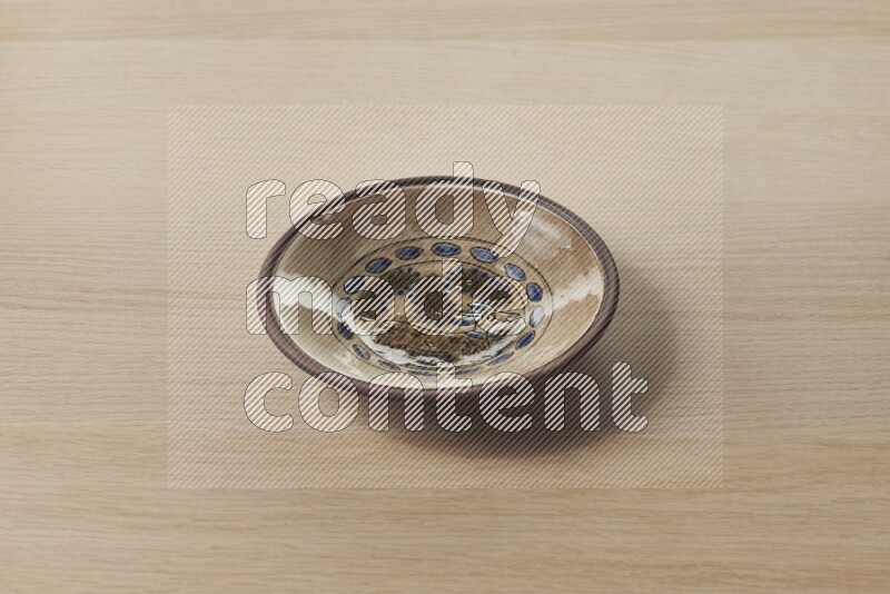 صحن فخاري مزخرف على خلفية خشبية فاتحة