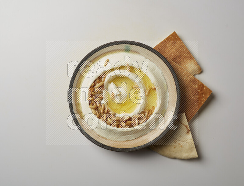 Lebnah garnished with pine nuts in a pottery plate on a white background