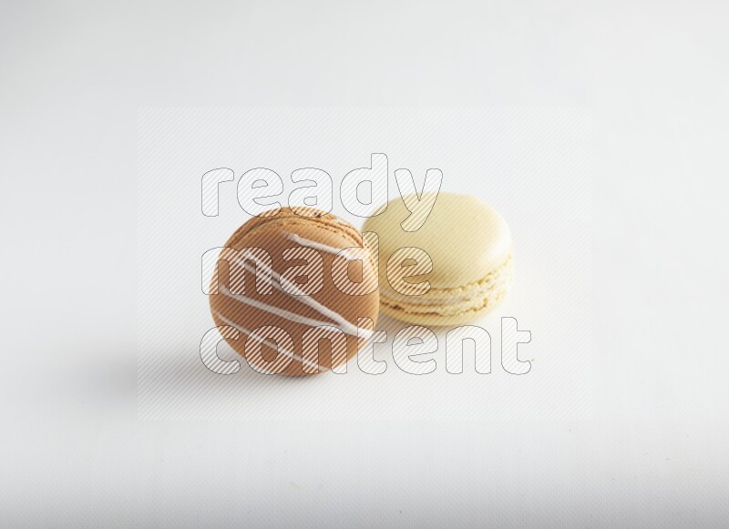 45º Shot of of two assorted Brown Irish Cream, and Yellow Vanilla macarons on white background