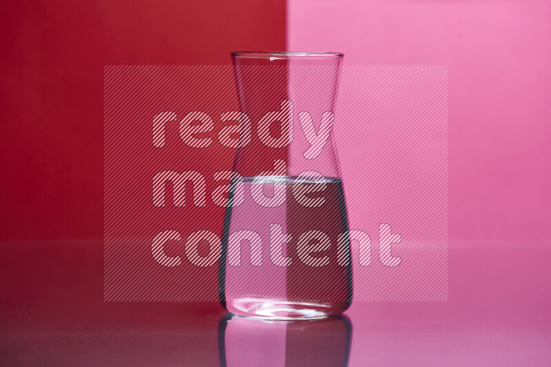 The image features a clear glassware filled with water, set against red and pink background