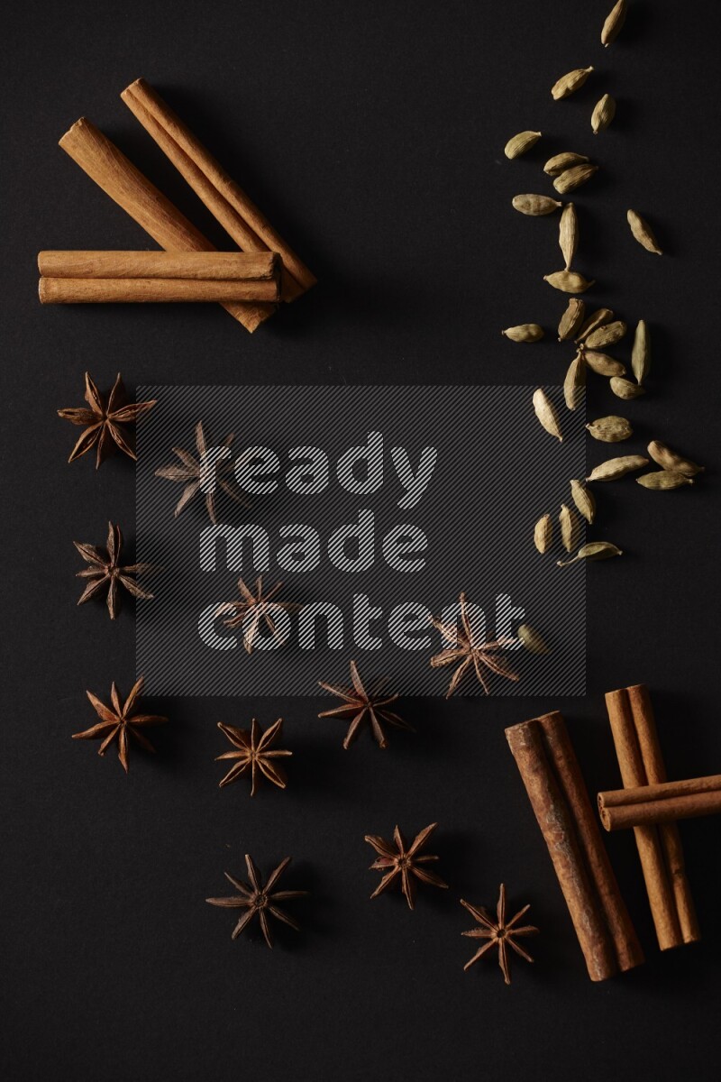 أعواد من القرفة وحبوب الهيل واليانسون النجمي علي خلفية سوداء