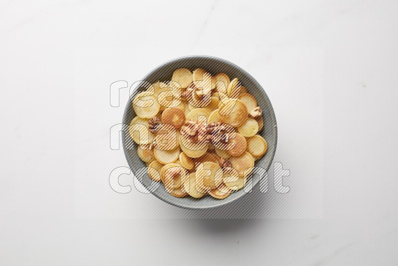 Top-view shot of walnut cereal pancakes in a round bowl on white background