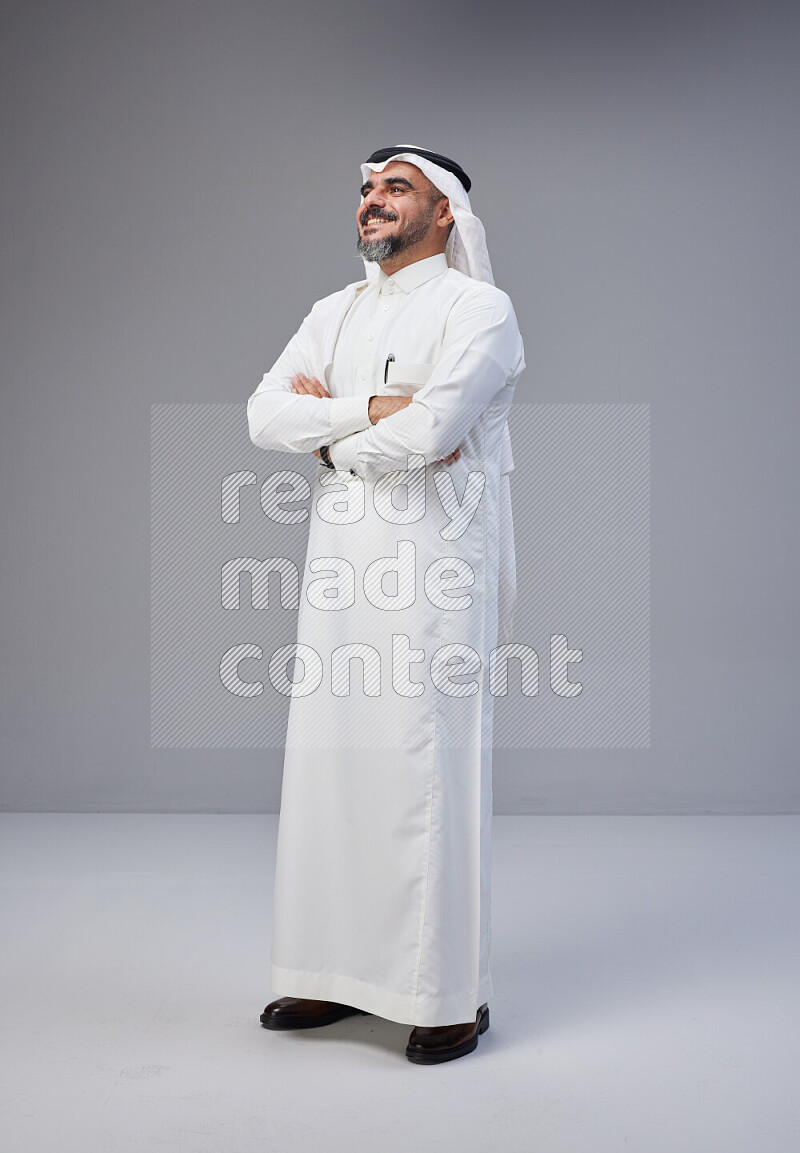 Saudi man Wearing Thob and white Shomag standing with crossed arms on Gray background