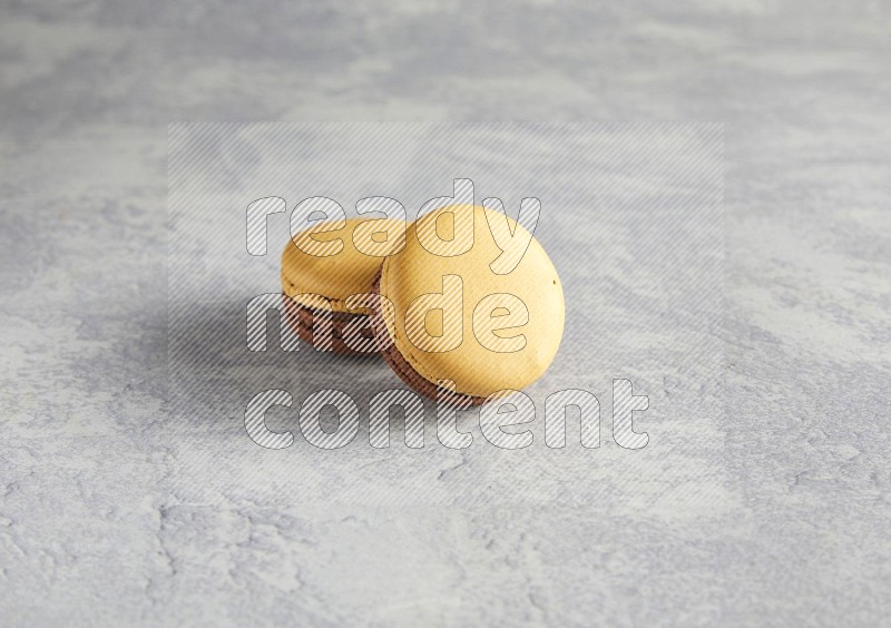 45º Shot of two Yellow and Brown Chai Latte macarons r on white  marble background