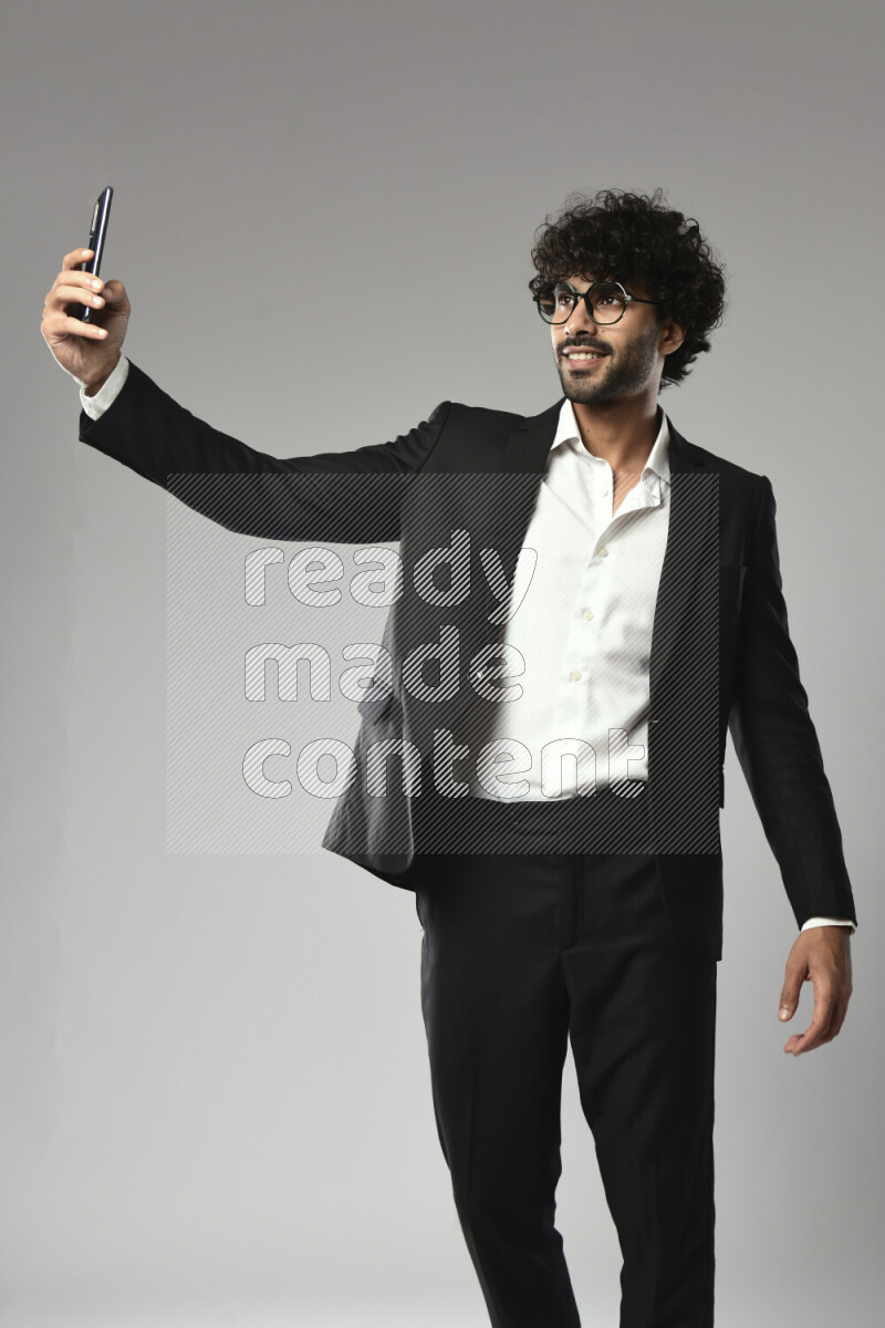 A man wearing formal standing and taking a selfie on white background