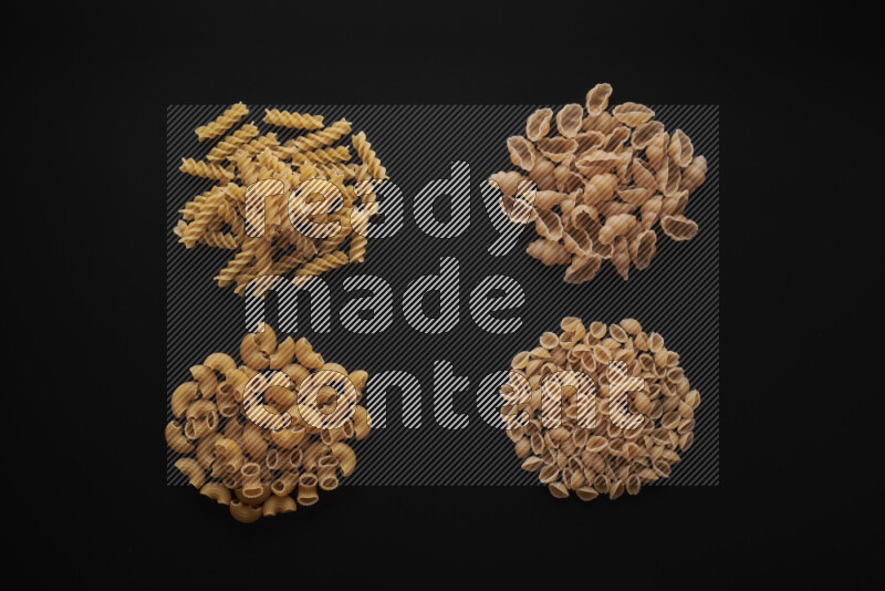 Different pasta types in bunches on black background