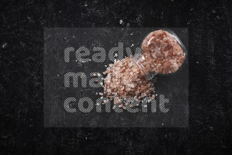 A glass jar full of coarse himalayan salt crystals on black background