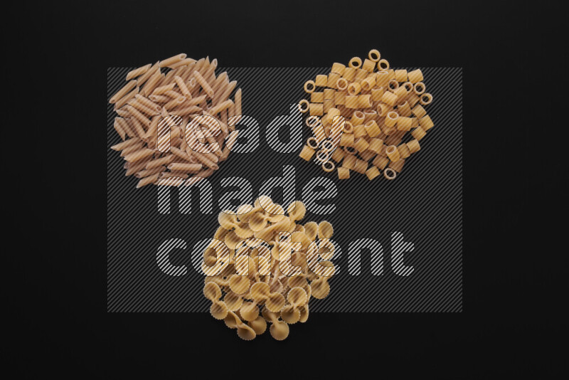 Different pasta types in bunches on black background