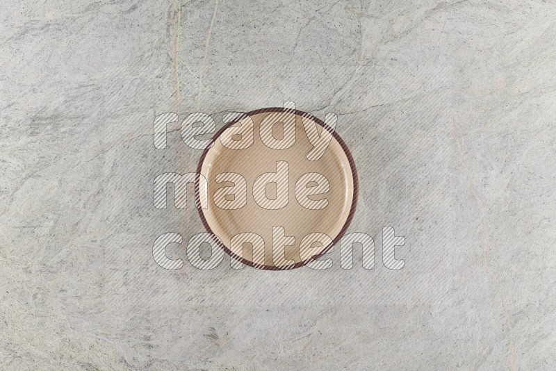 Top View Shot Of A Beige Pottery Oven Plate On Grey Marble Flooring