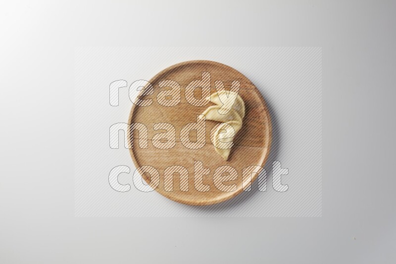 Three Sambosas on a wooden round plate on a white background