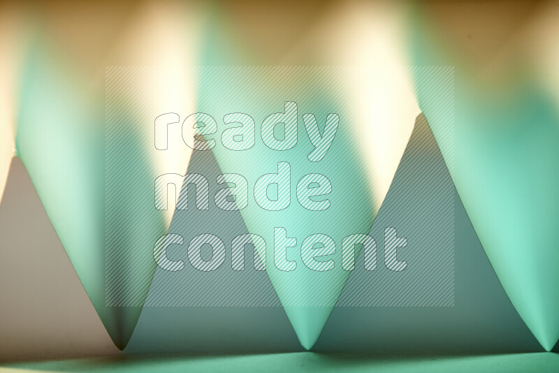 صورة مجردة مقربة تظهر طيات ورقية هندسية حادة بتدرجات اللون الأخضر مع درجات لونية دافئة