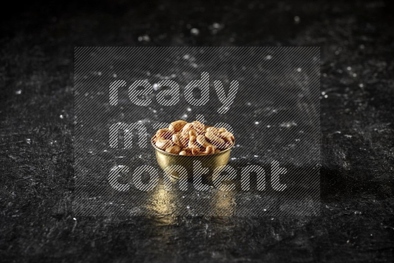 Nuts in a metal bowl in a dark setup