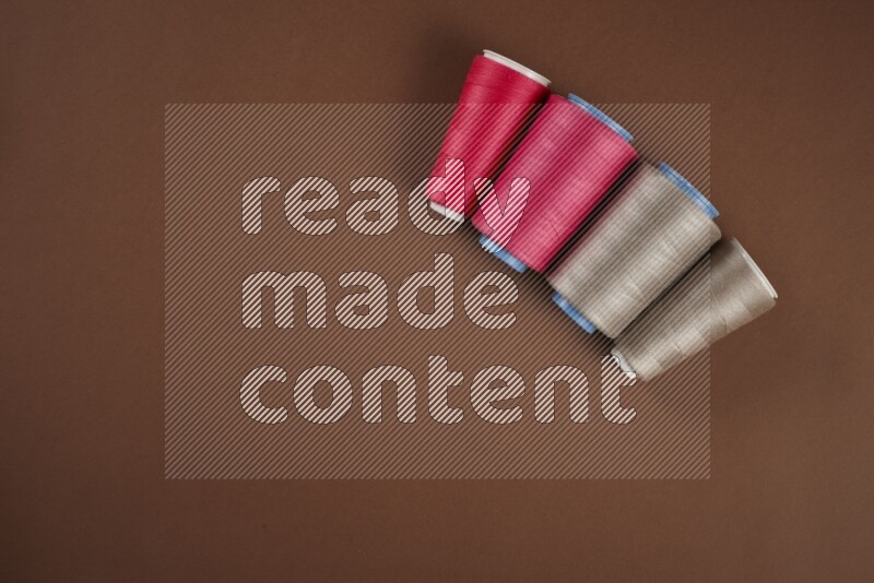 مجموعة من أدوات الخياطة والتفصيل زهرية اللون على خلفية بنية