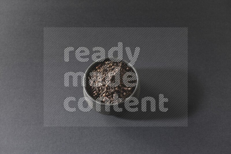 وعاء فخاري أسود ممتلئ بحبوب القرنفل علي خلفية سوداء