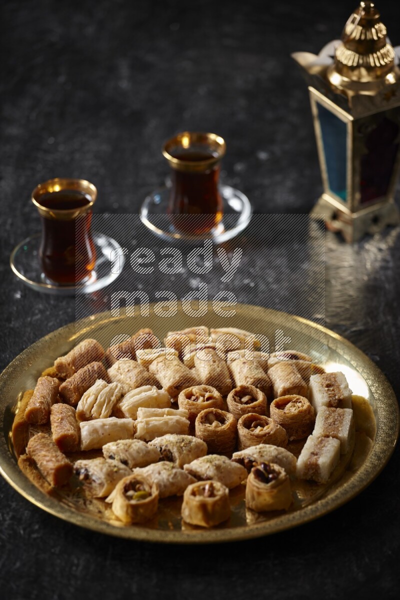 Oriental desserts with tea and a metal lantern in a dark setup