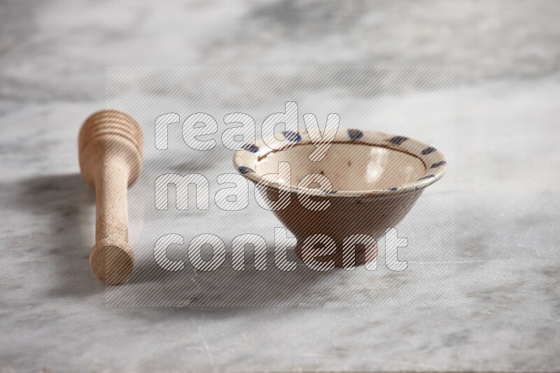 Decorative pottery bowl with wooden honey dipper on the side on grey marble background